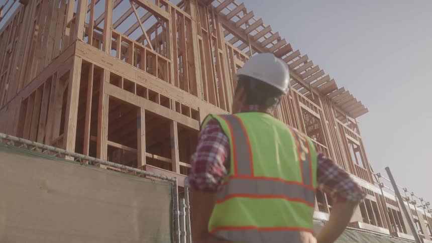 A construction worker inspects the wooden frame of a multistory building under construction