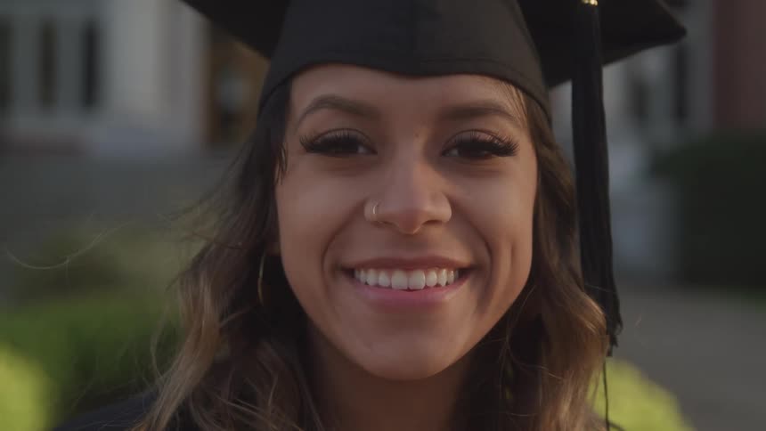 Happy female graduate smiling in her cap and gown