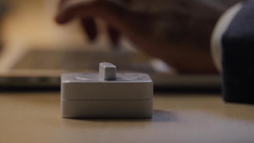 A person sets a timer on the table and begins typing on a laptop