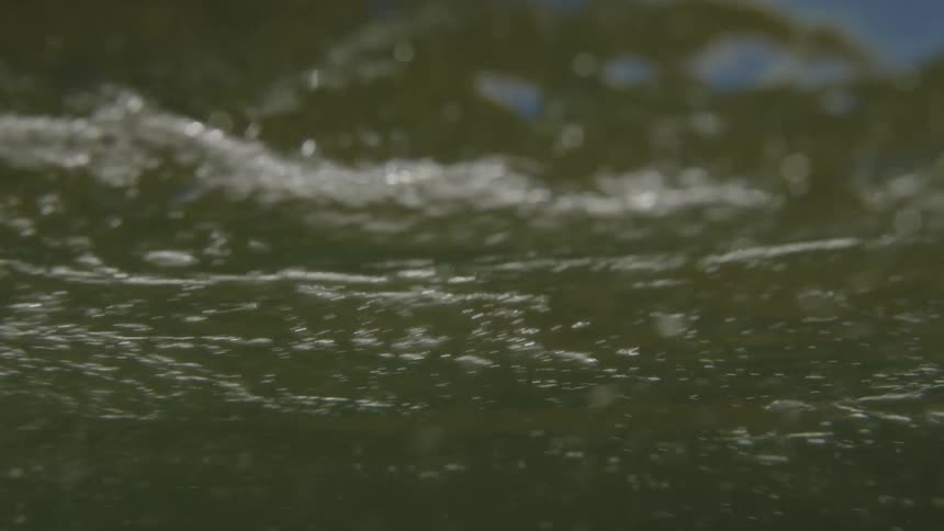 The view bobs at the oceans surface briefly dipping underwater before focusing on the sun sparkling across dark churning ripples