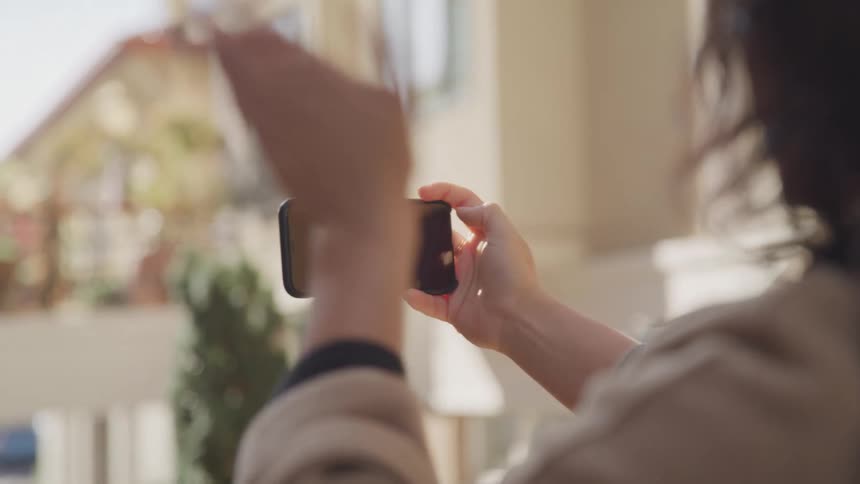 A woman waves at her phone