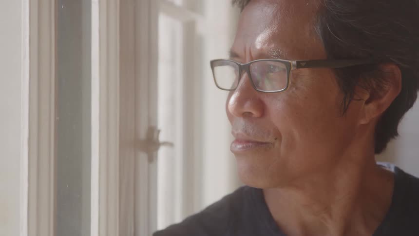 Man with glasses looking out the window