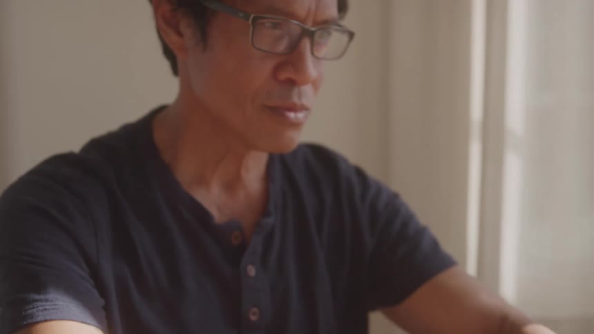 The man is reading and typing on a computer