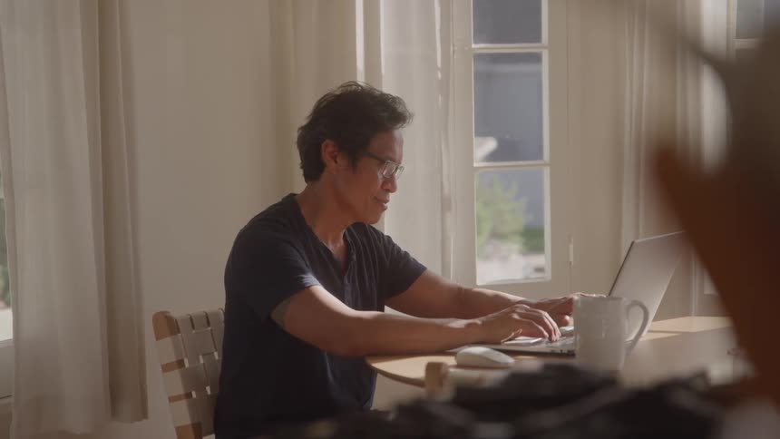 Man sitting at a desk typing on a laptop