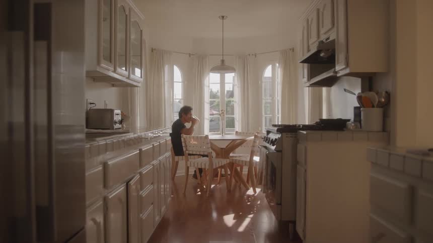 A man sits in the kitchen enjoying his coffee