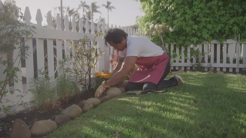 The man is planting flowers in his garden