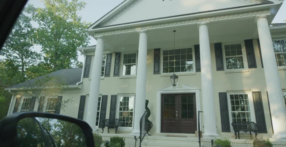 A large mansion is outside the car