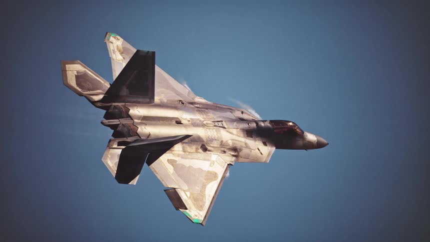 A grey fighter jet with its wings angled is captured mid flight against a clear blue sky