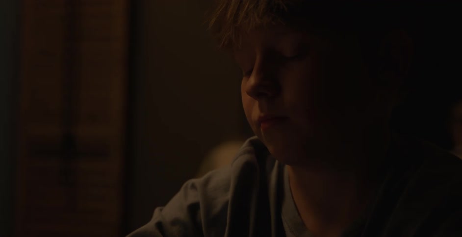 Boy in a dark room interacting with a smartphone