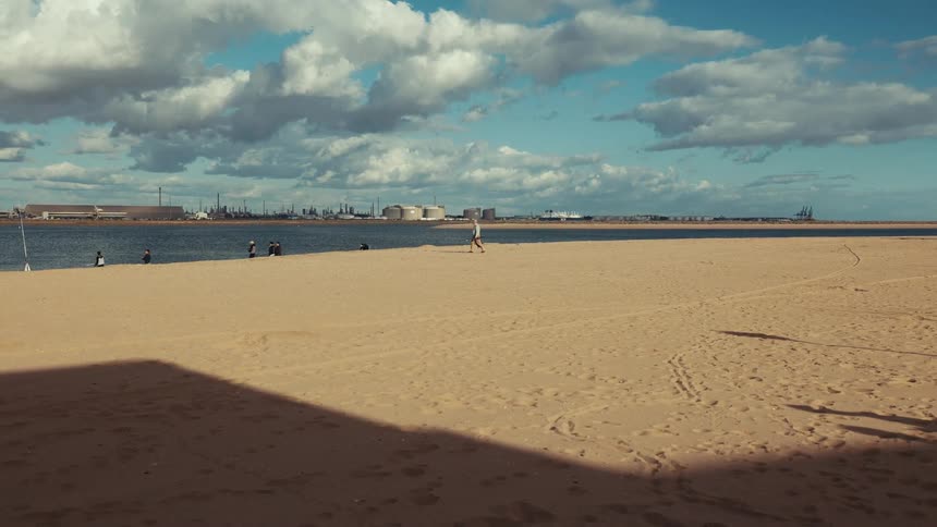 Long stretch of sand and some people on the edge of a lake