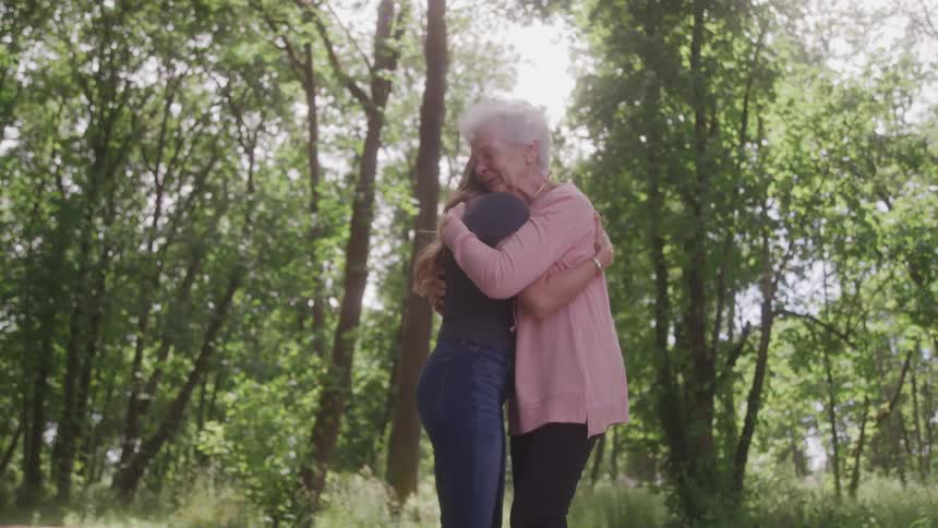 Two women are hugging by the forest