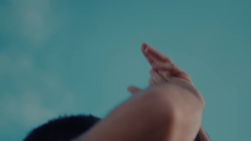 Man with hands in the air clapping under blue skies