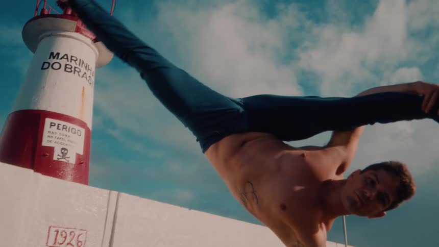 Man without a shirt and jeans doing a capoeira maneuver