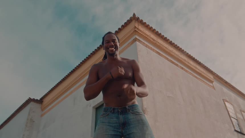 Smiling shirtless man dancing outdoors