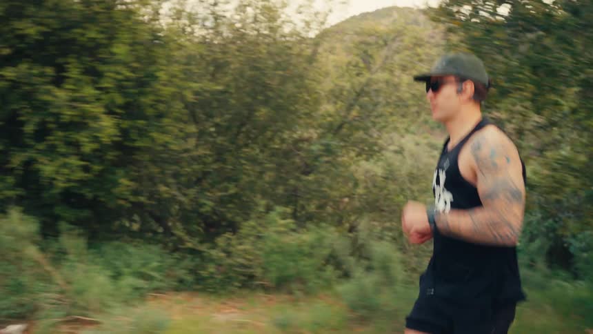 Man wearing a cap and glasses running in nature