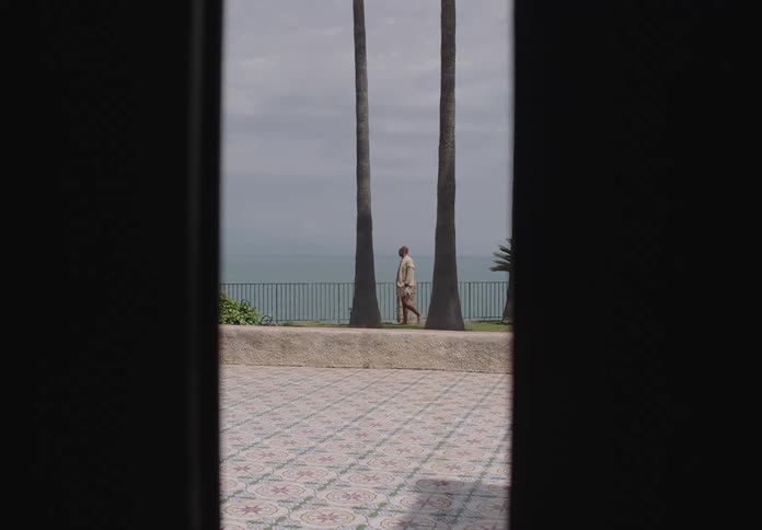 A man walks through an outdoor public parking lot by the coast on a sunny day