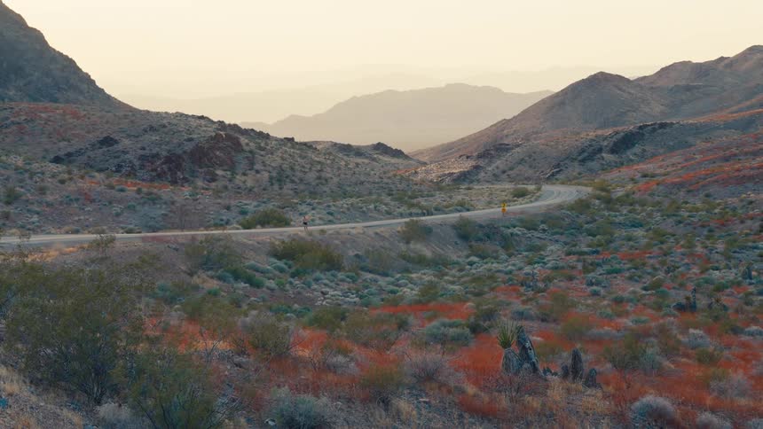 Jogger runs along a highway winding past fields of wildflowers and foggy mountains