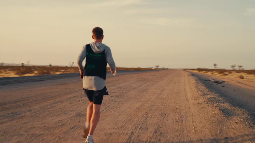 A m an is running on a dirt road in the desert