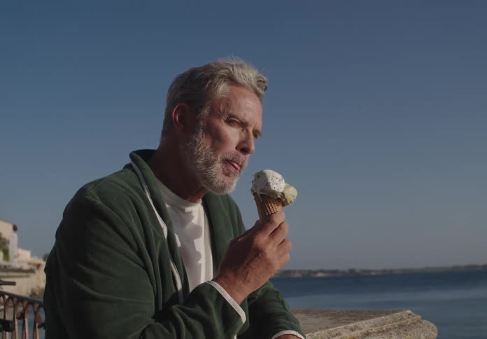 Man eating an ice cream cone overlooking the coast in italy