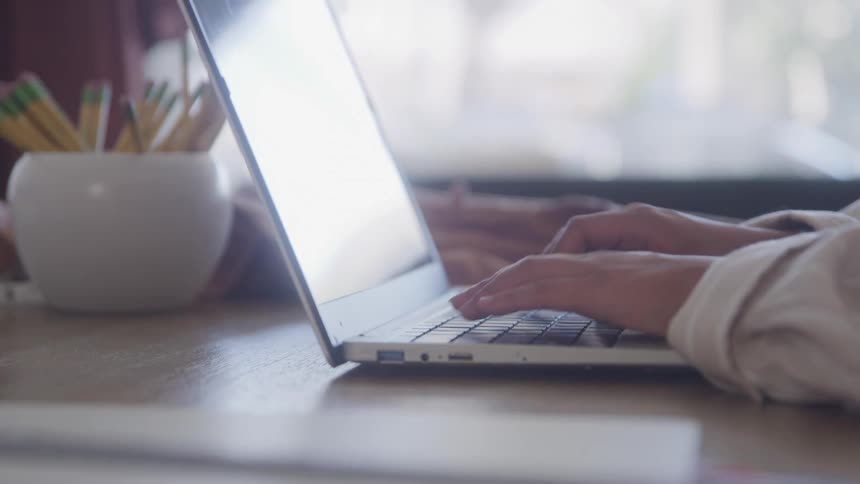 Hands typing on a laptop keyboard
