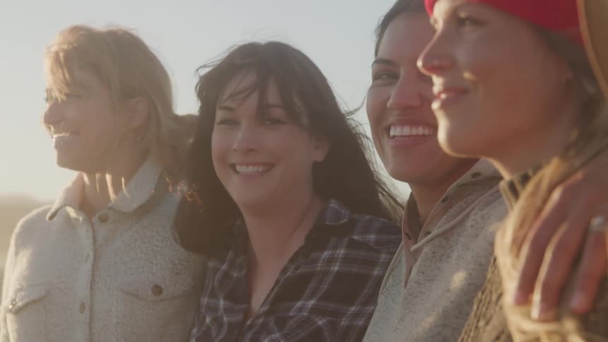 Four women are smiling while enjoying the sunrise