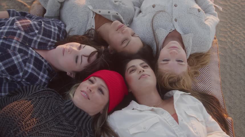 Group of women lying on a cushion in the sand