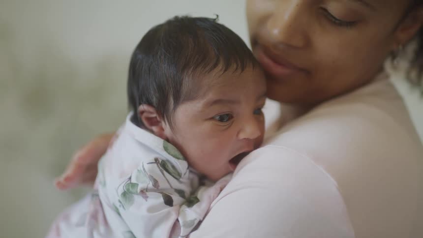 Close up of mother carrying and pampering her baby on her chest