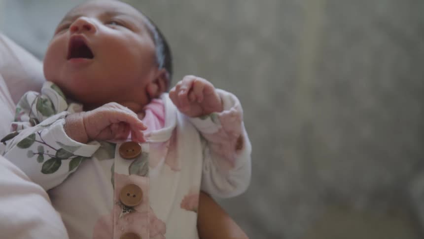 A person holds a baby in their arms