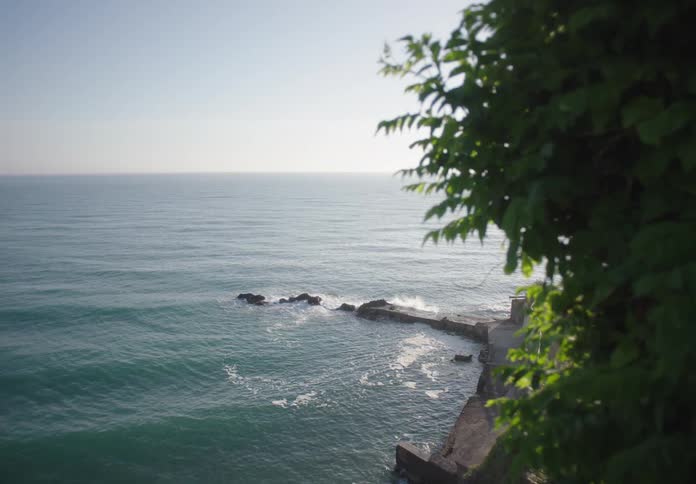 Calm ocean waves hit rocks by a stone jetty