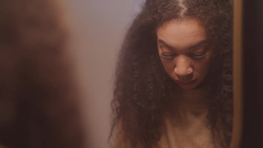 The woman looks into the mirror then down