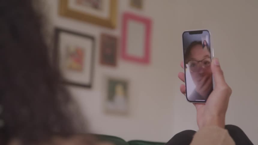 Woman holding a smartphone and on a video call with another person