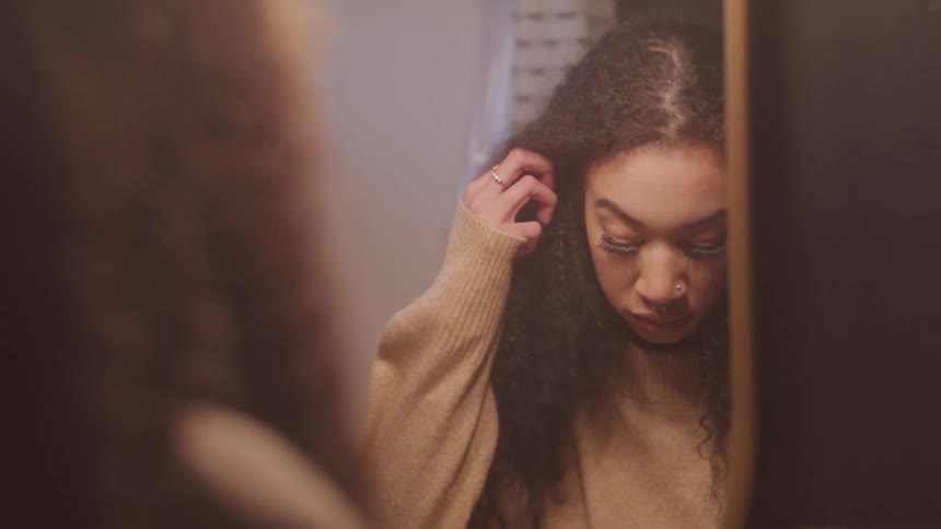 A woman is looking at herself in the mirror