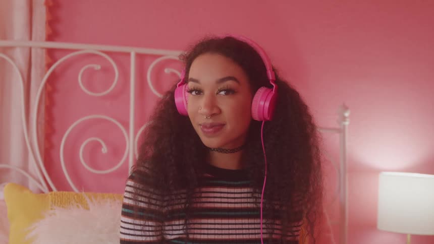A girl sits on her bed listening to music