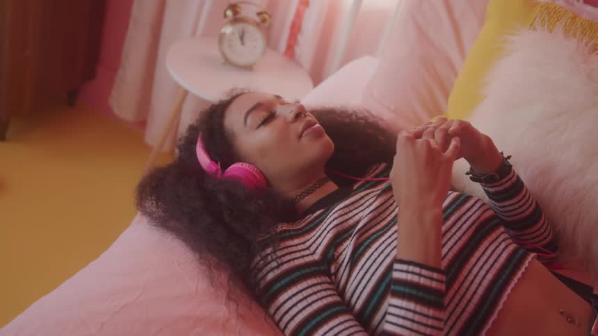 The woman is listening to music while laying down