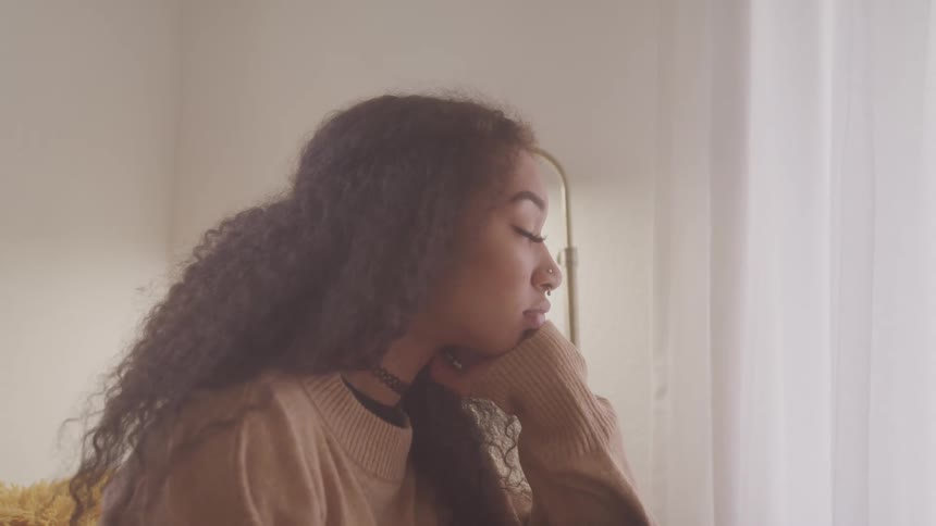 The woman is resting while facing the window