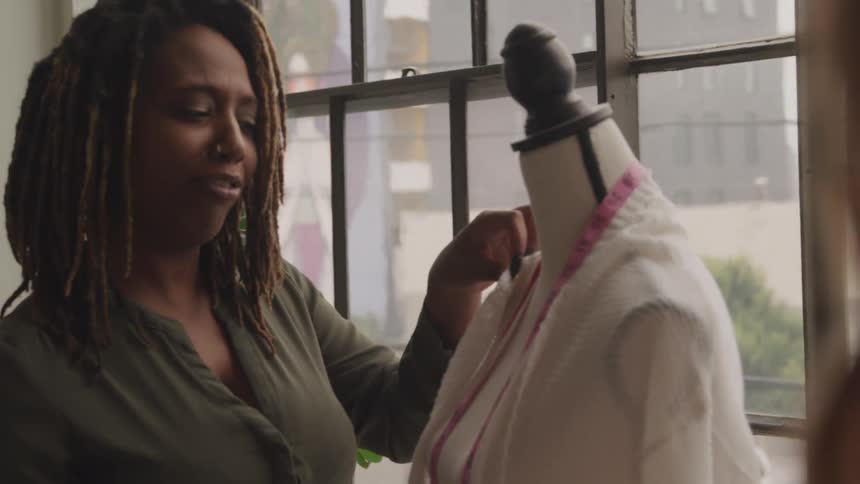 Two women talk about the clothing on a mannequin