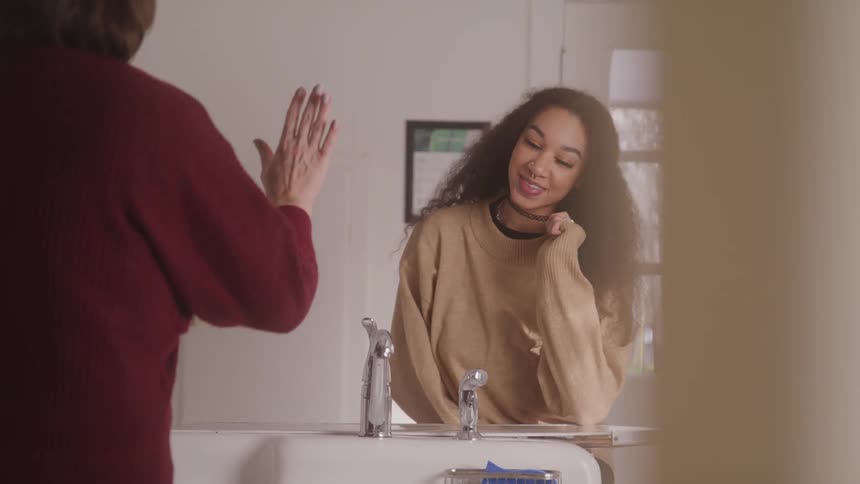 Two women are in the kitchen around midday with one of them washing the dishes
