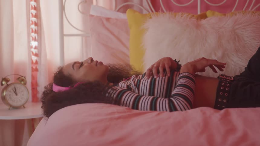A girl lies on her bed listening to music