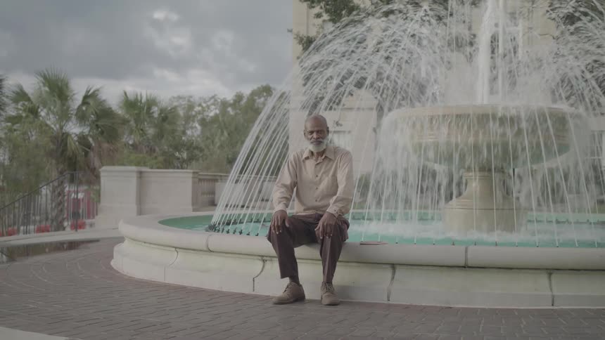 Bearded man sitting on a fountain