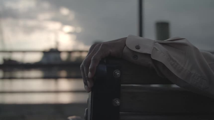 A man sits on a bench by the water