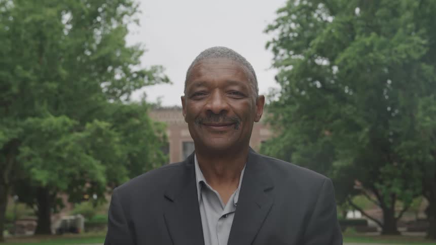 Man with happy facial expression outdoors posing in a grey blazer