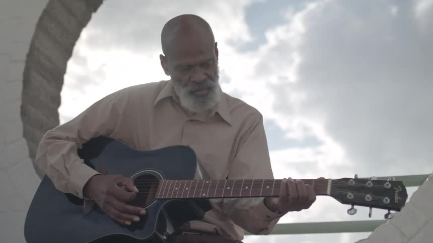 Man sitting outdoors playing guitar