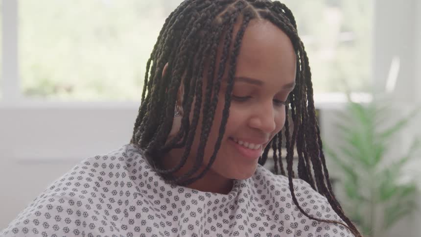 Female patient in hospital gown with happy expression in a room