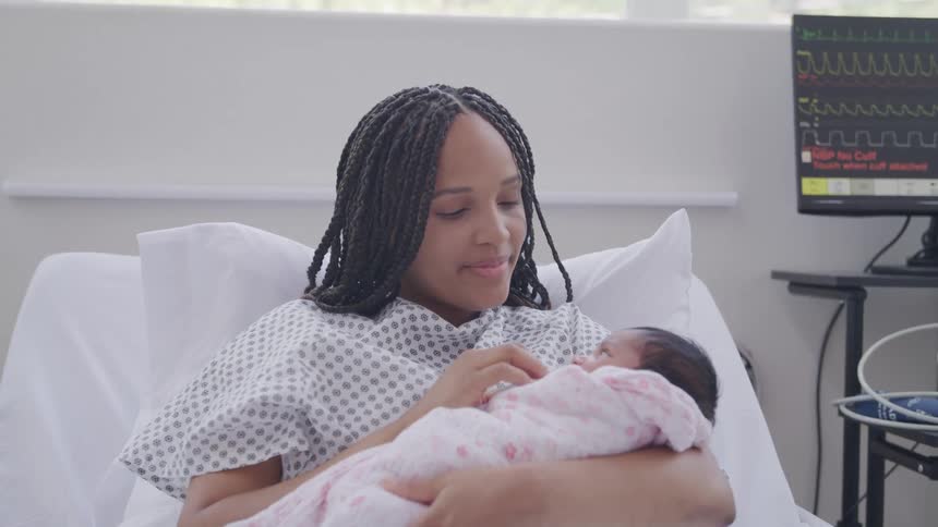 New mom sitting in a hospital bed holding her newborn baby girl