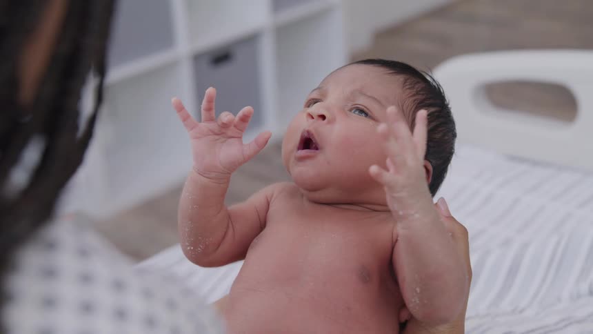 A mother is holding her crying newborn