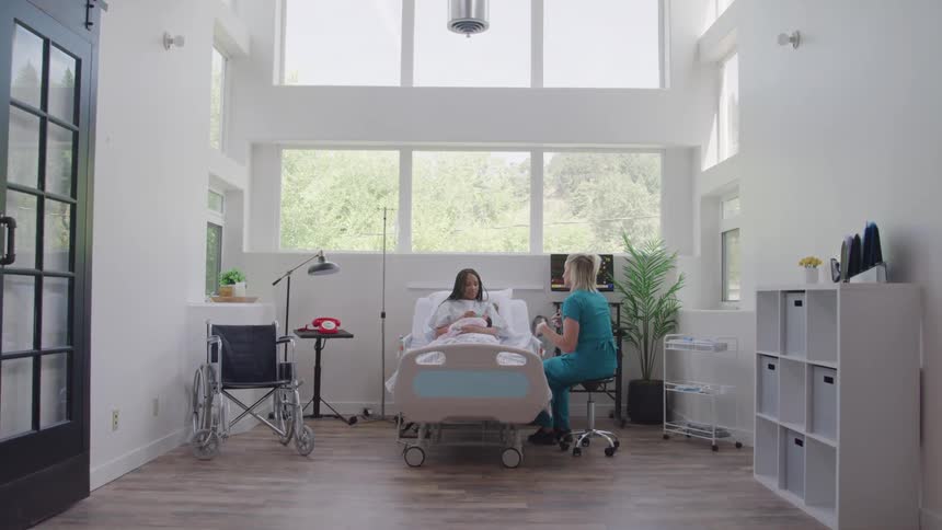 Nurse talking to a patient holding a newborn baby in a hospital room