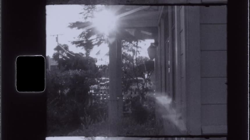 Sun flares over a house porch in an archival black and white shot