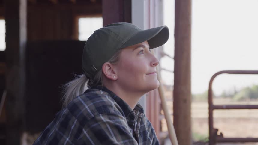 Woman wearing a cap with a happy expression in a farming environment