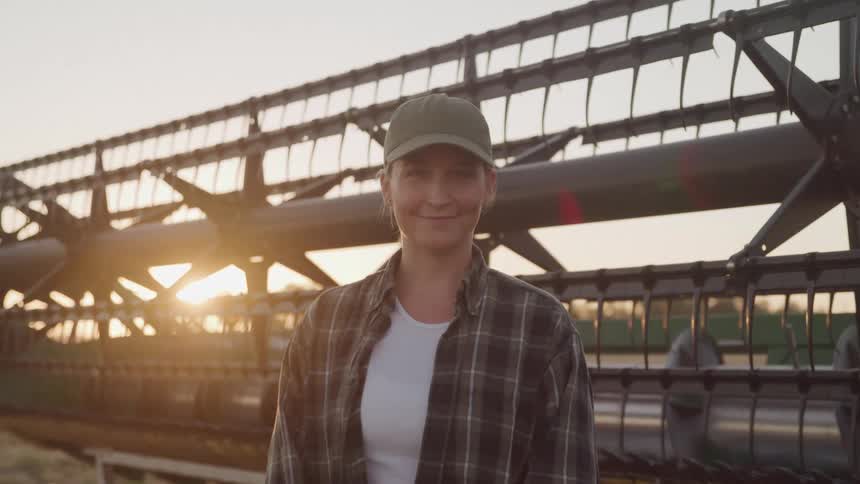 Woman wearing a cap next to agricultural machinery