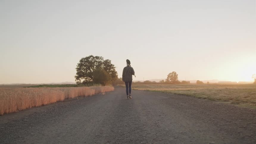 Woman walks alone on a countryside road at sunrise